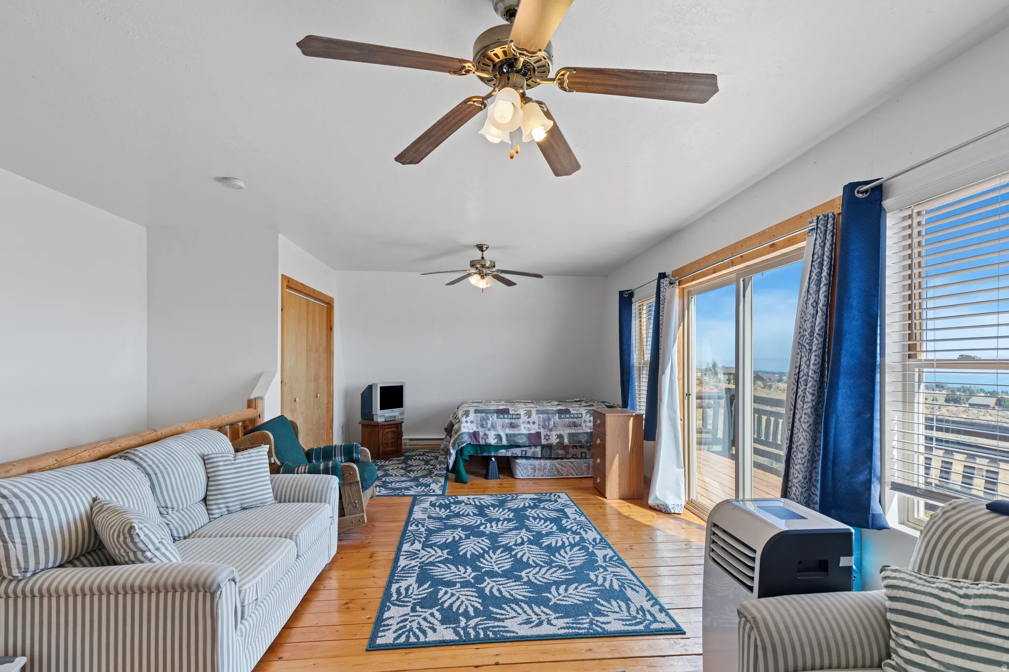 Wood-finish flooring, white walls, and a ceiling fan with integrated lighting