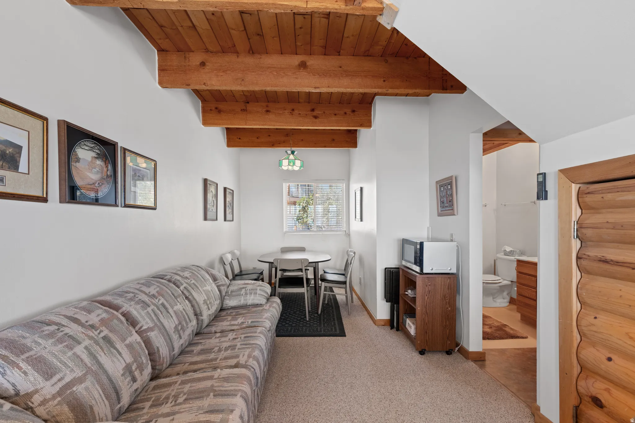 Exposed wood beam ceiling, white painted walls, and wood-trim doorway