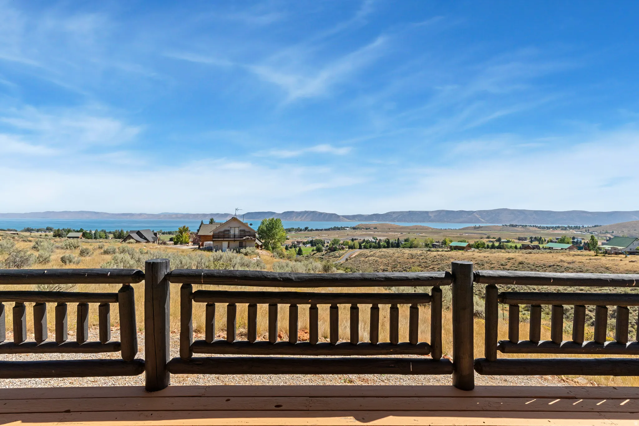 Expansive outdoor decking featuring a rustic wood railing and commanding water and mountain scenery
