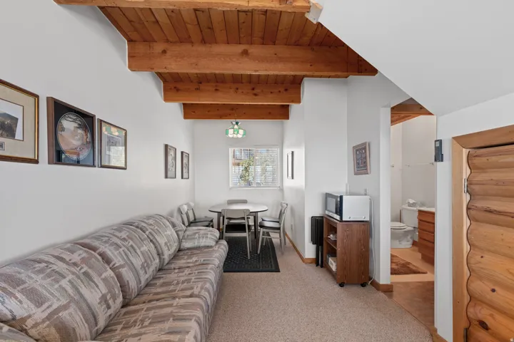 Exposed wood beam ceiling, white painted walls, and wood-trim doorway