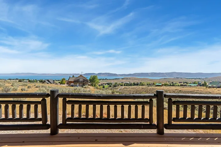 Expansive outdoor decking featuring a rustic wood railing and commanding water and mountain scenery
