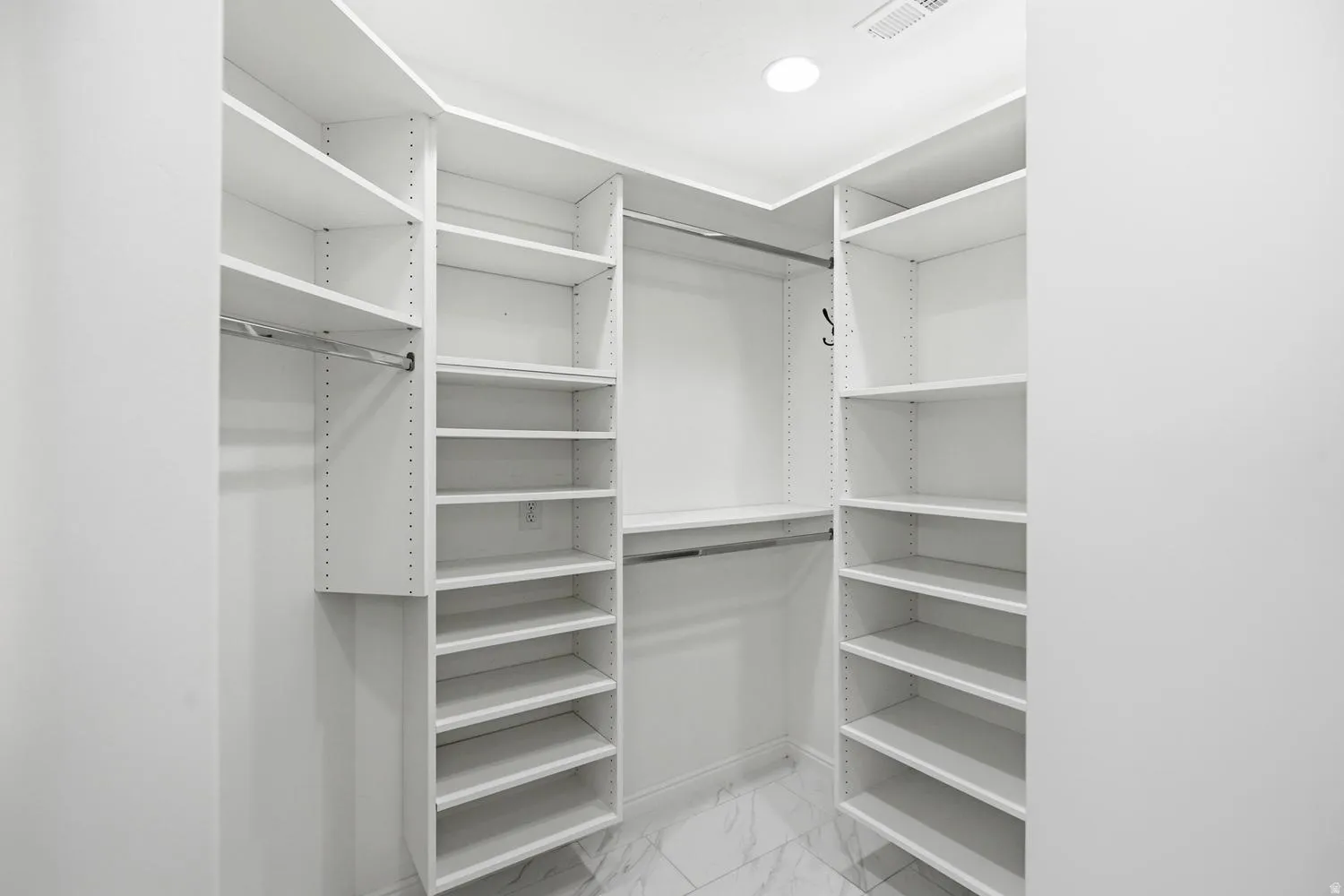 Built-in closet system featuring multiple shelving units, integrated hanging rods, and recessed lighting