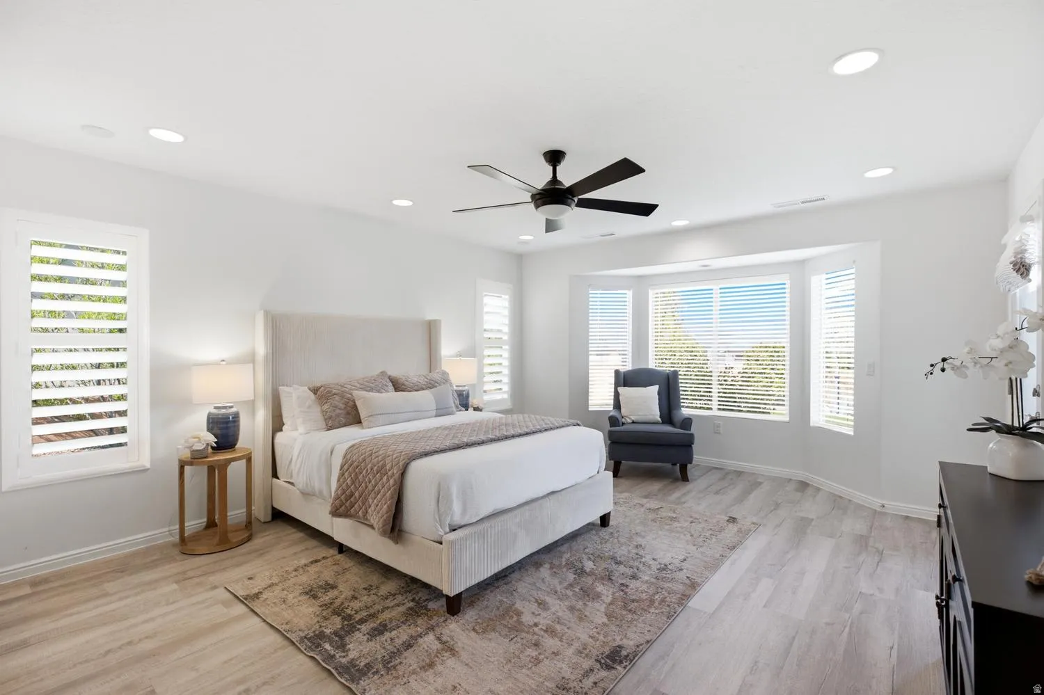 Recessed lighting, ceiling fan, bay window, wood-finish flooring, and white plantation shutters