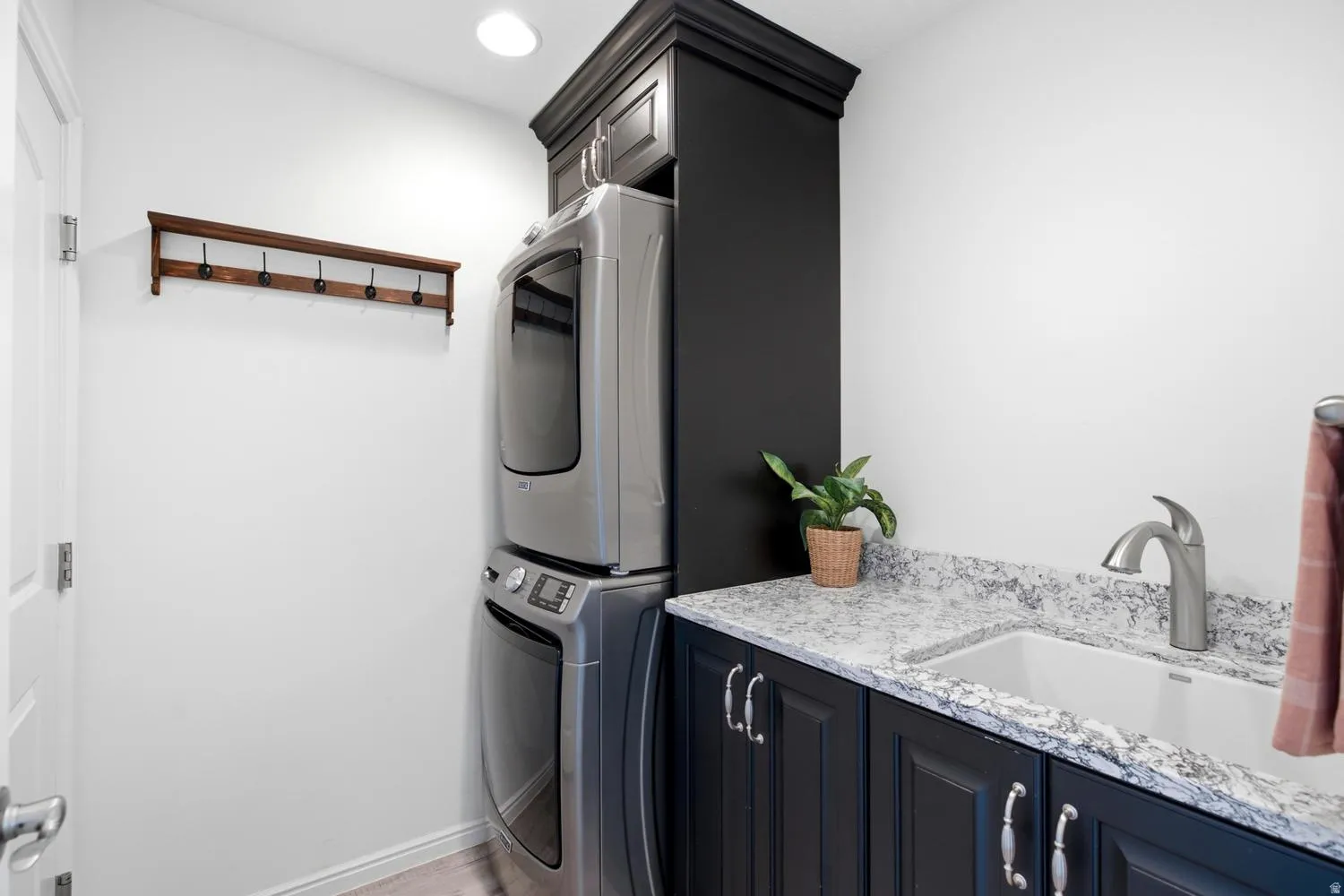 Laundry space featuring a built-in utility sink, dark cabinetry, and a light-colored countertop