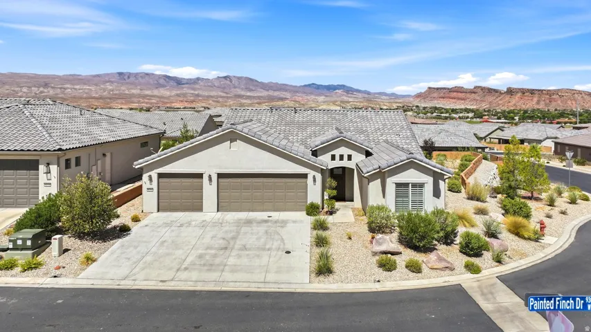 Siding exterior with a tile roof, an attached two-car garage, and desert-style landscaping