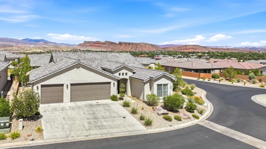 Stucco exterior with a tiled roof, two-car garage, and desert-inspired landscaping