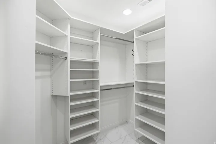 Built-in closet system featuring multiple shelving units, integrated hanging rods, and recessed lighting