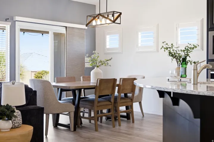 Open-concept living space with wood-finish flooring and a contemporary linear chandelier