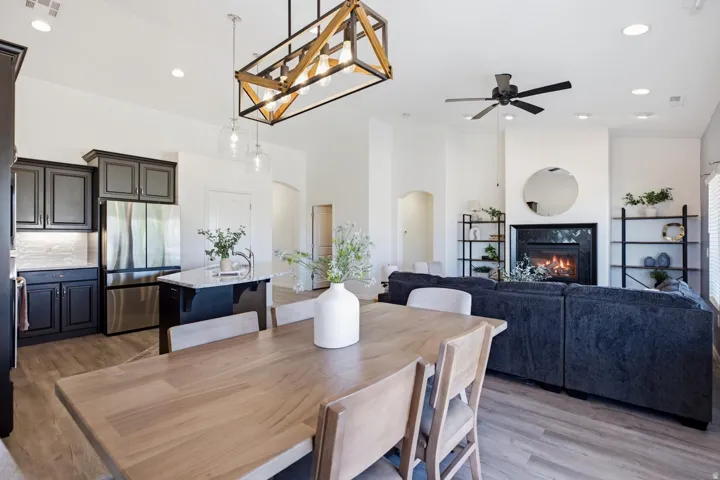 Open-concept living space featuring wood-finish flooring, a contemporary fireplace with a sleek surround, and a kitchen with dark cabinetry, stainless steel appliances, and a central island