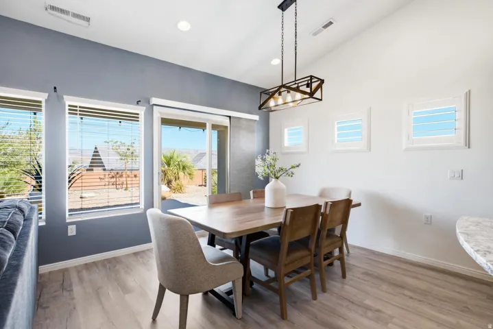 Vaulted ceilings, wood-finish flooring, sliding glass door, recessed lighting, and a modern rectangular chandelier