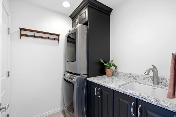 Laundry space featuring a built-in utility sink, dark cabinetry, and a light-colored countertop