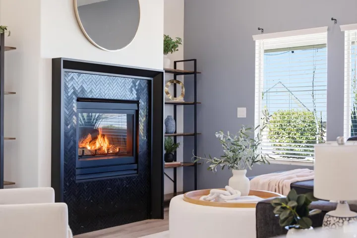 Built-in fireplace with a black herringbone tile surround, a wall-mounted round mirror, and a wall-mounted shelving unit