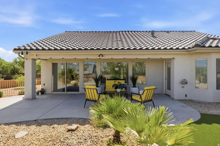 Covered patio with tile roofing, multiple sliding glass doors, and desert landscaping
