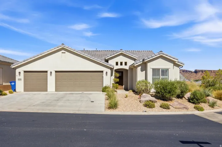 Stucco exterior with a tiled roof, two-car garage, and desert-style landscaping