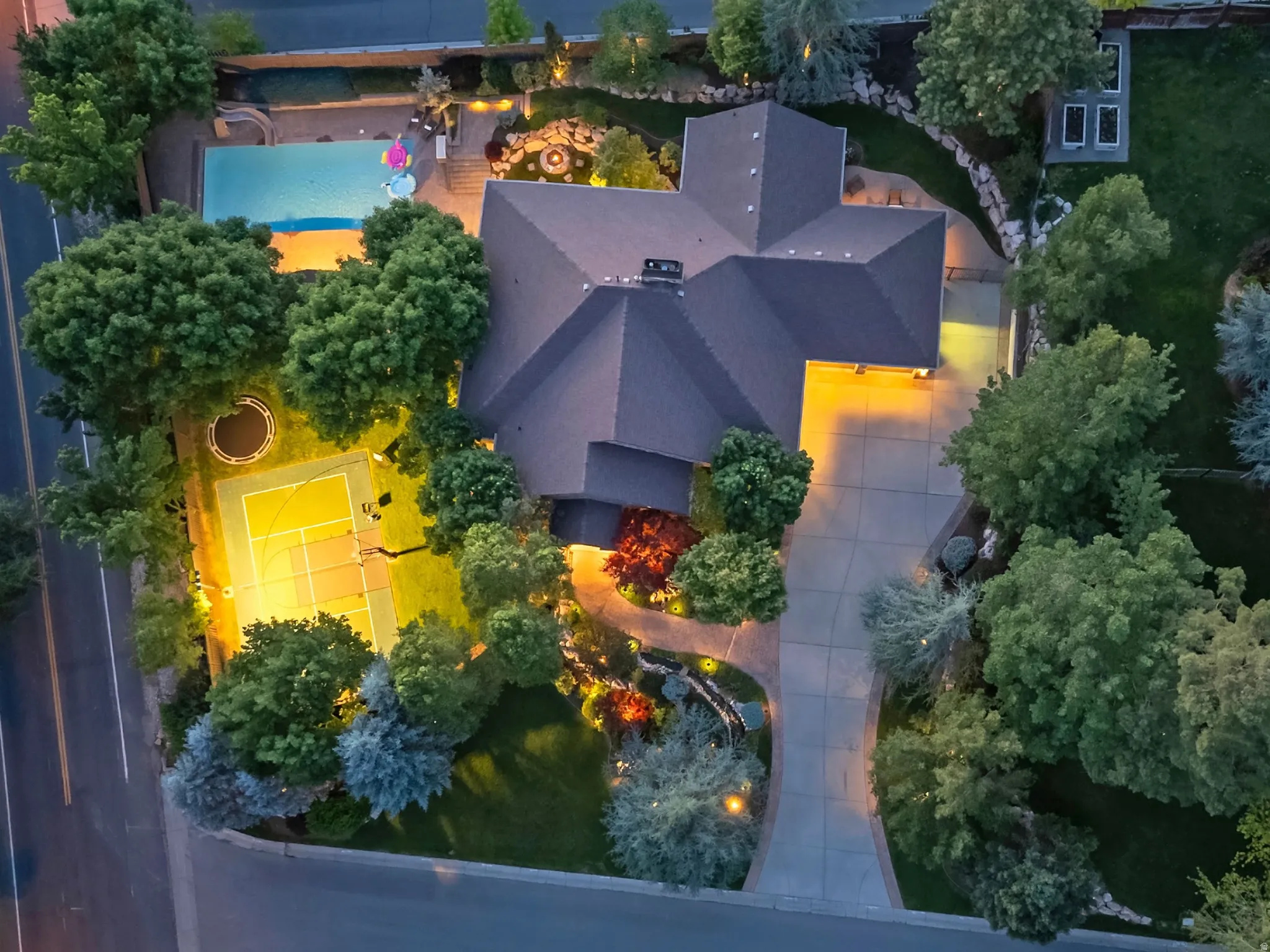 Expansive property featuring a swimming pool, tennis court, fire pit, and mature landscaping