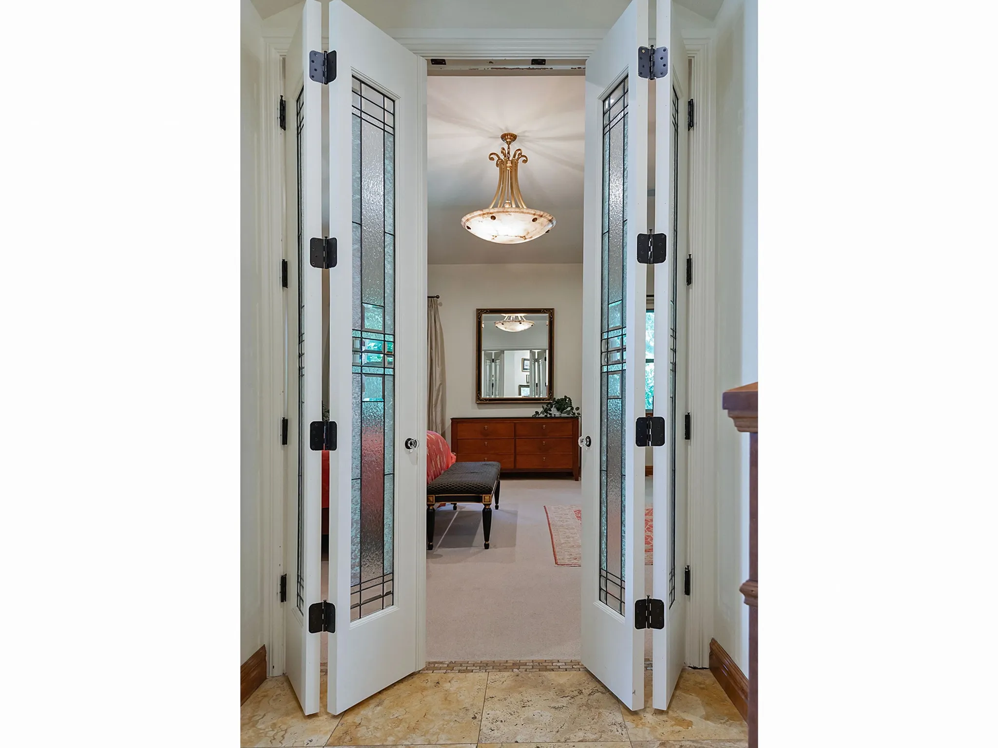Primary Bedroom French doors with decorative glass panels and dark hardware