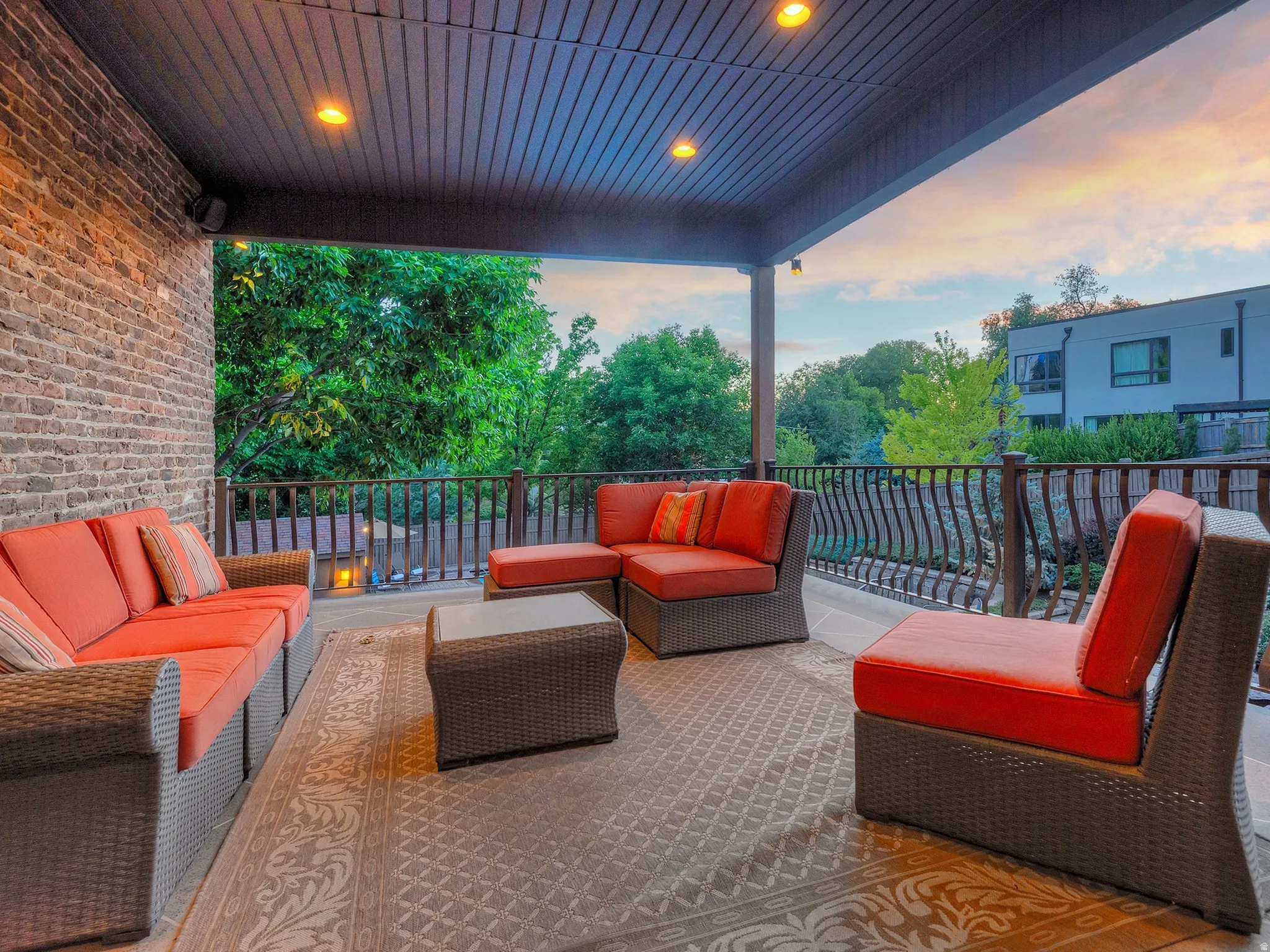 Covered patio featuring a brick wall, recessed lighting, and ornate metal railings