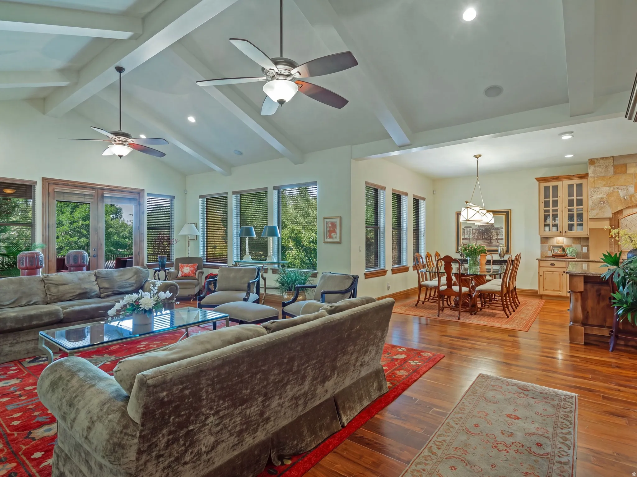 Vaulted ceiling with exposed beams, recessed lighting, and ceiling fans