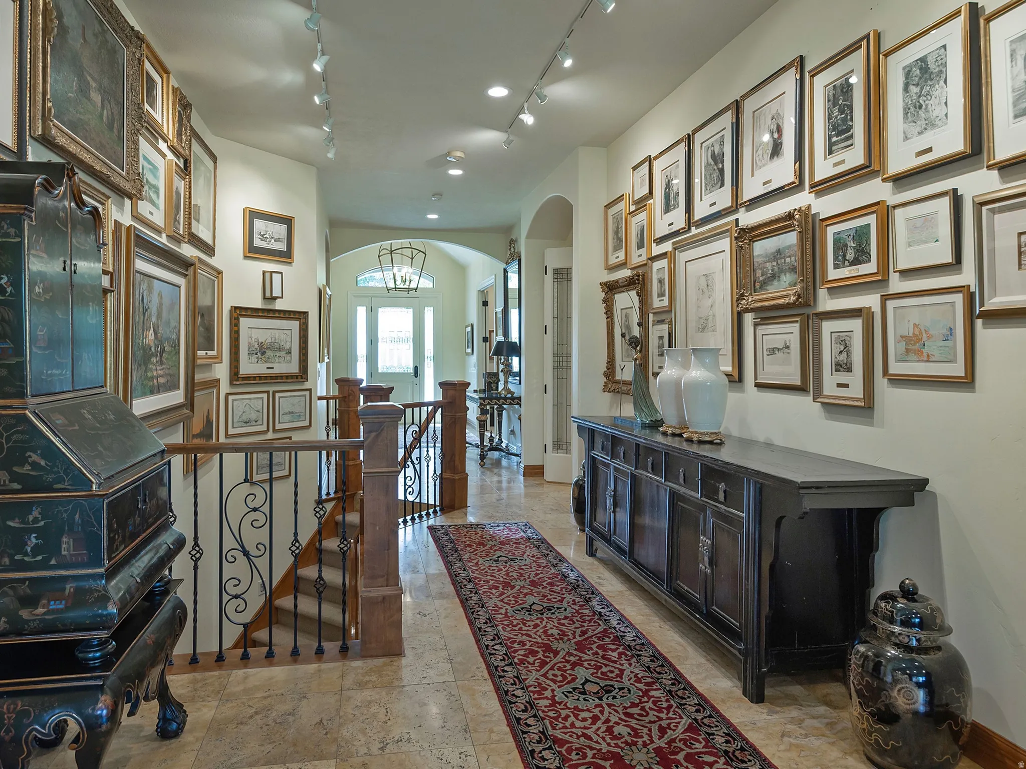 Hallway featuring tile flooring, track lighting, and an arched entryway