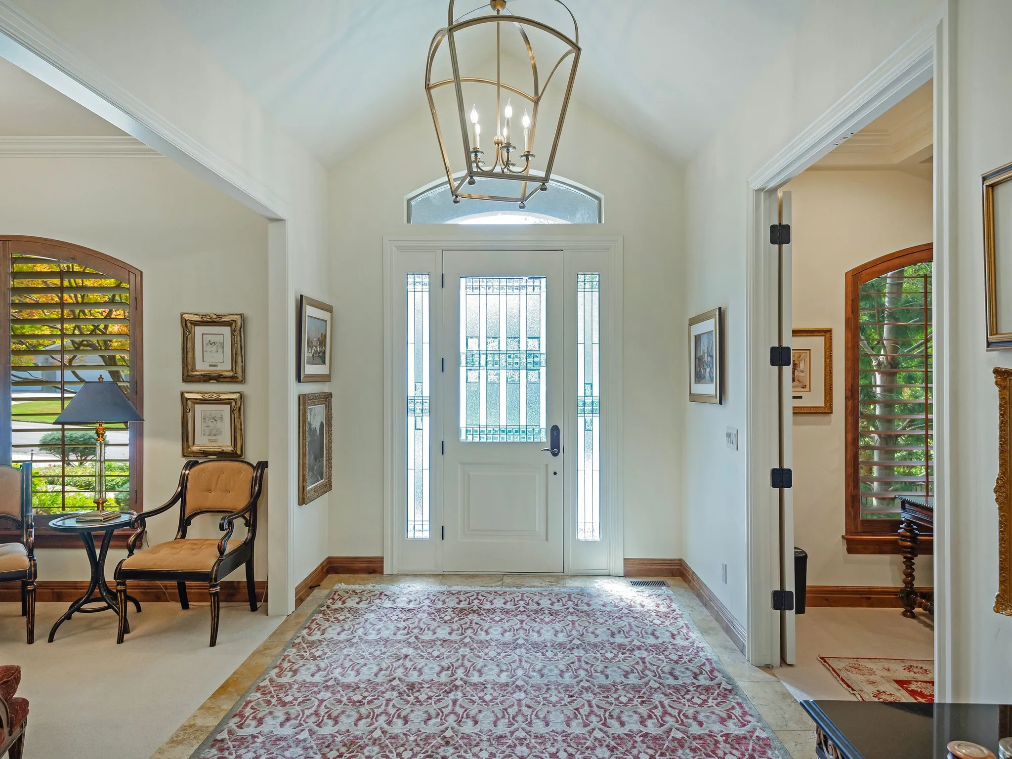 Grand entry with vaulted ceilings, decorative front door, side lights, transom window, and a large chandelier