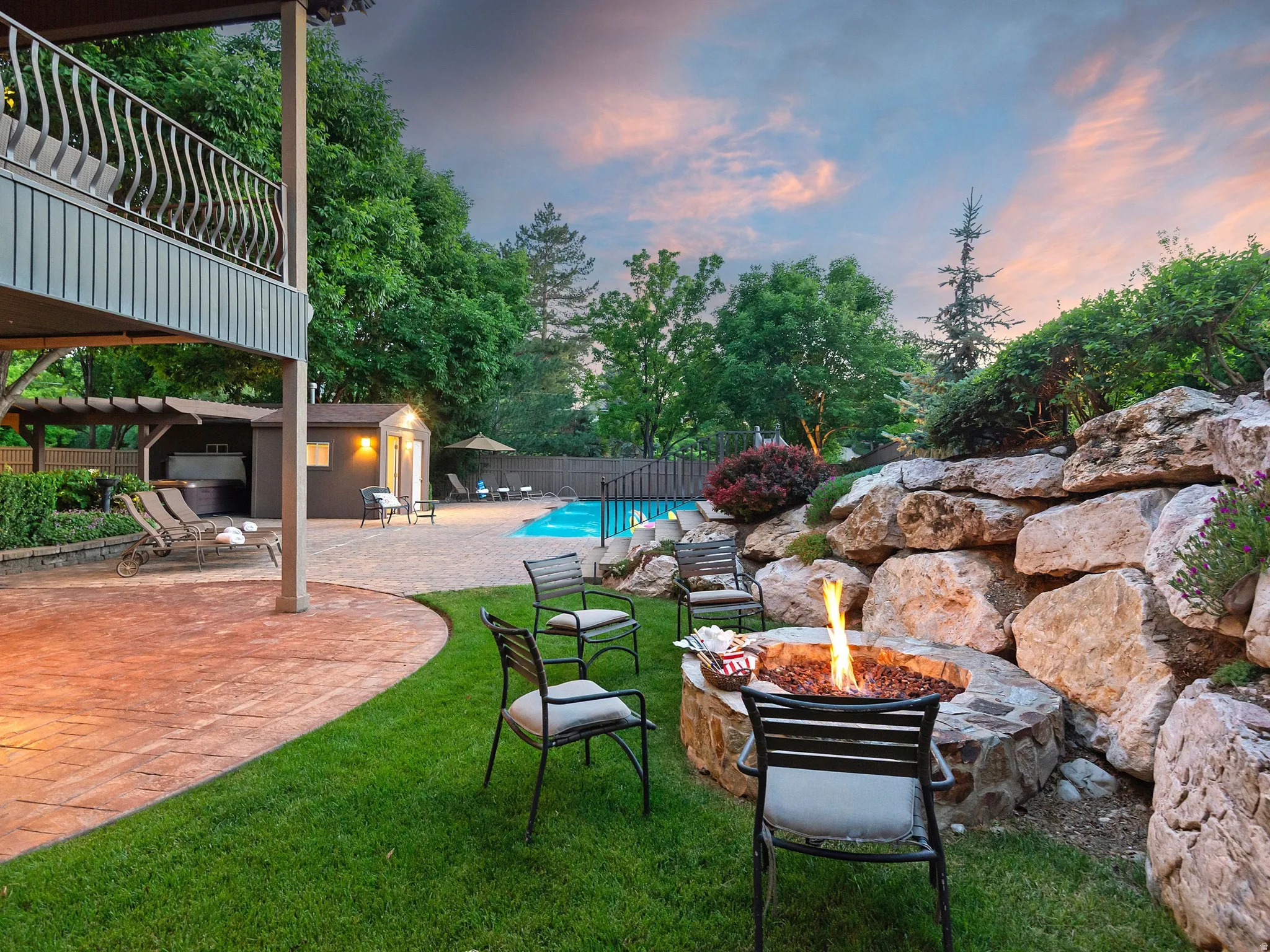 Expansive outdoor living area featuring a built-in fire pit, stone retaining wall, and a swimming pool W/Bath House