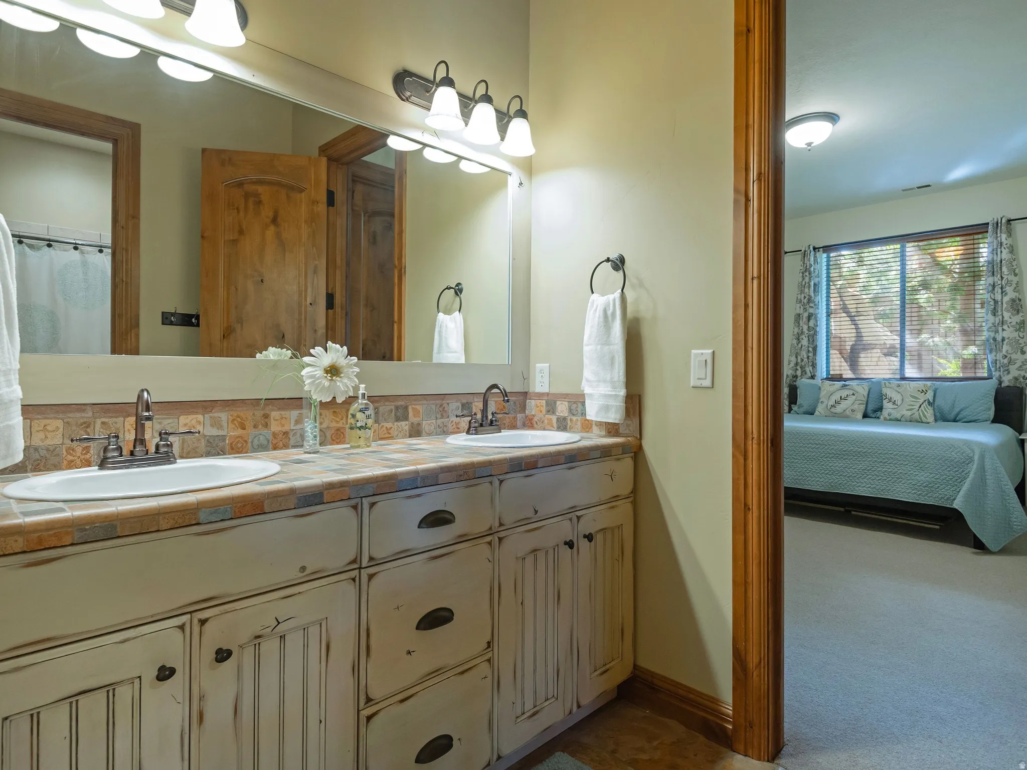 Dual vanity with integrated sinks, tiled countertop, and distressed wood-finish cabinetry