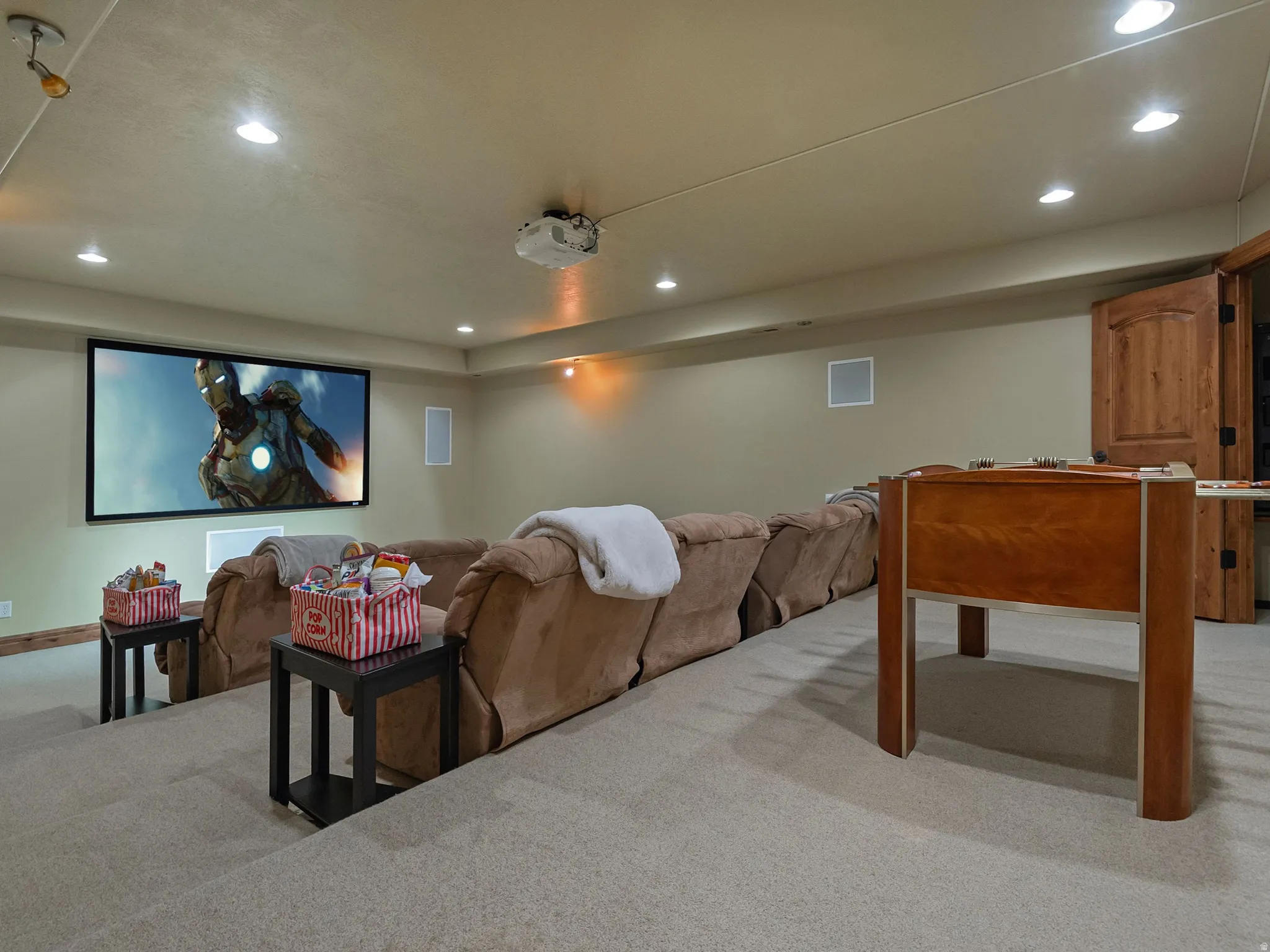 Dedicated media room featuring a large projection screen, integrated ceiling speakers, recessed lighting, and a tiered floor design