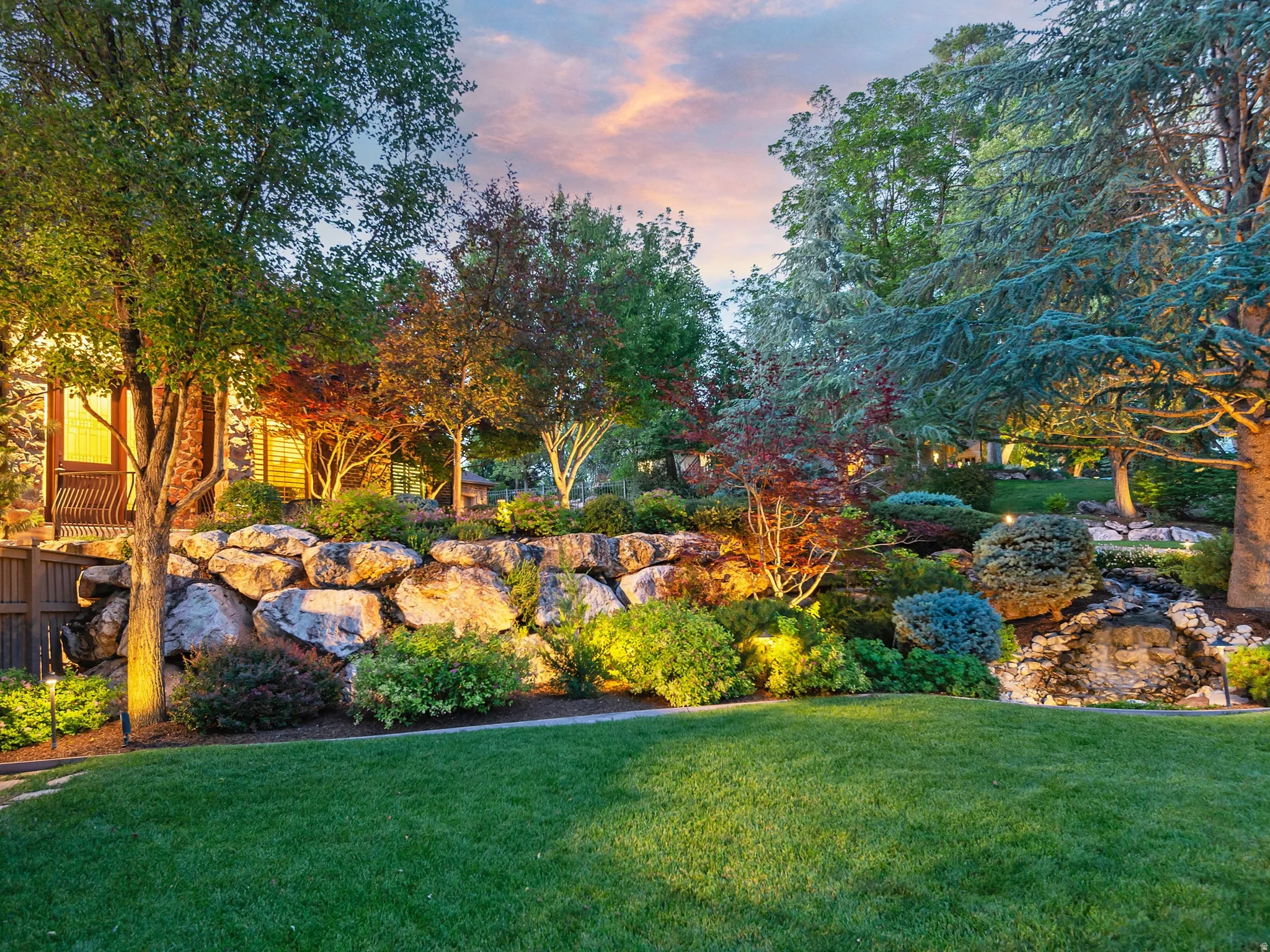 Expansive manicured lawn with a rock retaining wall and integrated landscaping
