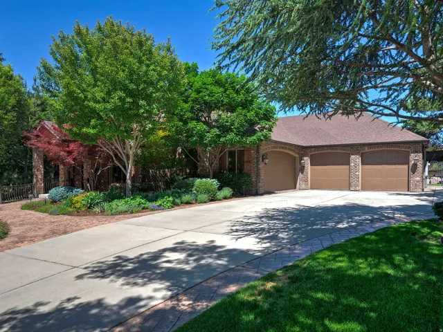 Brick exterior with a Four-car garage, concrete driveway, and mature landscaping