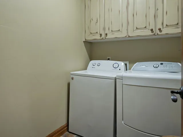 Built-in upper cabinetry with distressed finish, wood-finish base trim, and a solid wood door with dark hardware