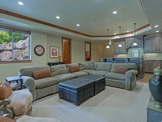 Recessed lighting, wood-finish trim, built-in wet bar with pendant lighting, wood-finish cabinetry, and a window with rock landscaping outside
