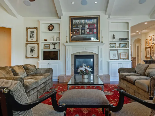 Built-in cabinetry flanking a fireplace with a stone surround, a coffered ceiling, and recessed lighting