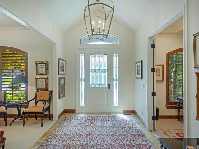 Grand entry with vaulted ceilings, decorative front door, side lights, transom window, and a large chandelier