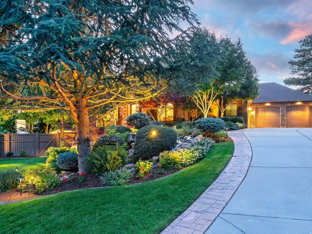 Expansive front yard with manicured lawn, established landscaping, and mature trees