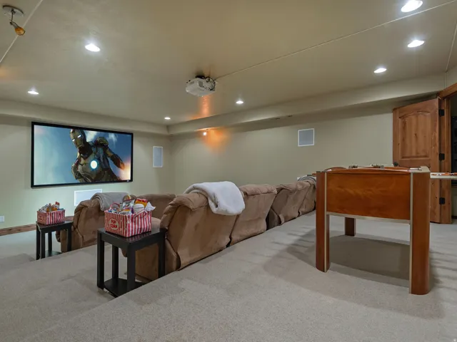 Dedicated media room featuring a large projection screen, integrated ceiling speakers, recessed lighting, and a tiered floor design