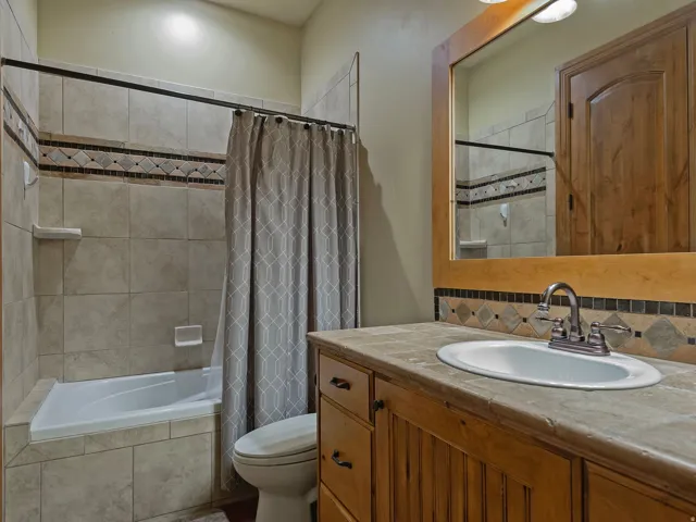 Built-in vanity with wood cabinetry, integrated sink, and stone-look countertop