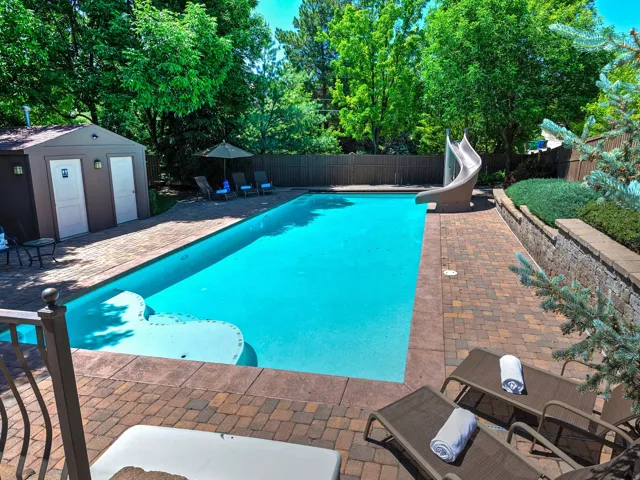 Private swimming pool with a pool slide, paver patio, retaining wall, and a dedicated pool house