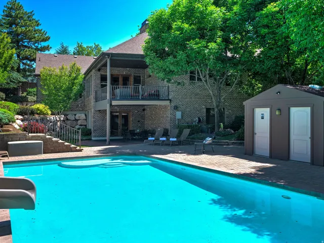 Expansive outdoor space featuring a swimming pool with a slide, a paved patio, and a two-story brick exterior with a covered balcony