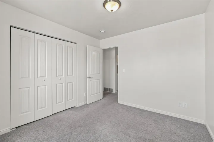 Soft gray carpeting, white painted walls, and a ceiling-mounted light fixture