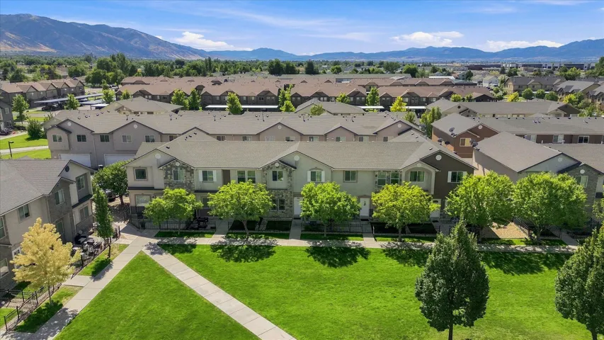 Townhome community with mountain backdrop, featuring landscaped grounds, mature trees, and paved pathways