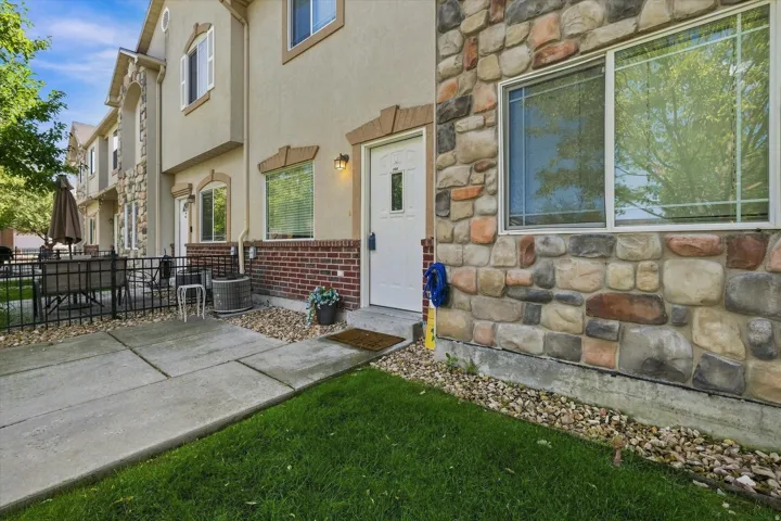 Stone veneer facade, stucco exterior, concrete patio, grass lawn, and decorative gravel landscaping
