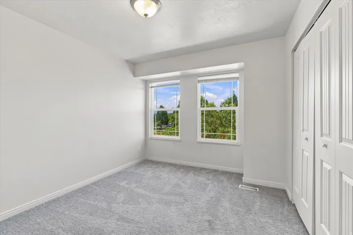 Plush gray carpet, dual windows, and bifold closet doors