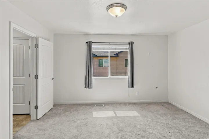 Neutral tone wall paint, flush mount ceiling light fixture, framed window, paneled interior doors, and gray carpet