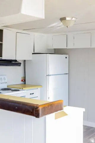 Kitchen featuring white cabinetry, a white refrigerator, a white electric range, and light-toned countertops
