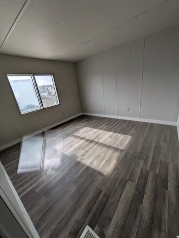 Dark wood-finish flooring with a subtle grain pattern, vertical paneled walls, and a multi-pane window