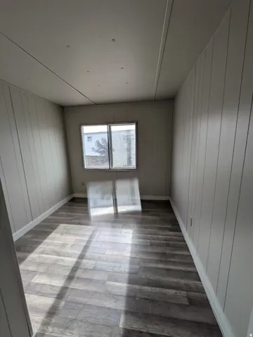 Wood-finish flooring with white trim and paneled walls