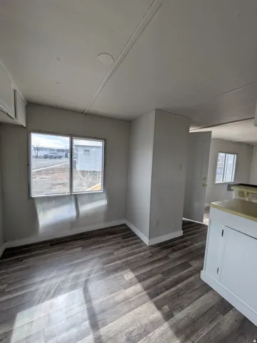 Wood-finish flooring, white paneled walls, and built-in cabinetry with a light-colored countertop