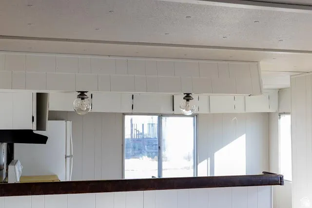 White paneling, built-in lighting, kitchen cabinetry, and a refrigerator