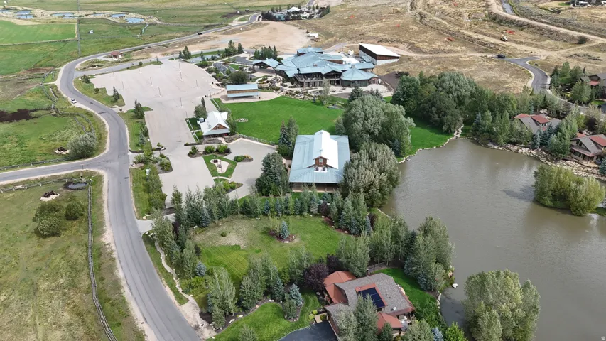Extensive property featuring a large body of water, paved roadways, and multiple structures set amongst green spaces and mature trees