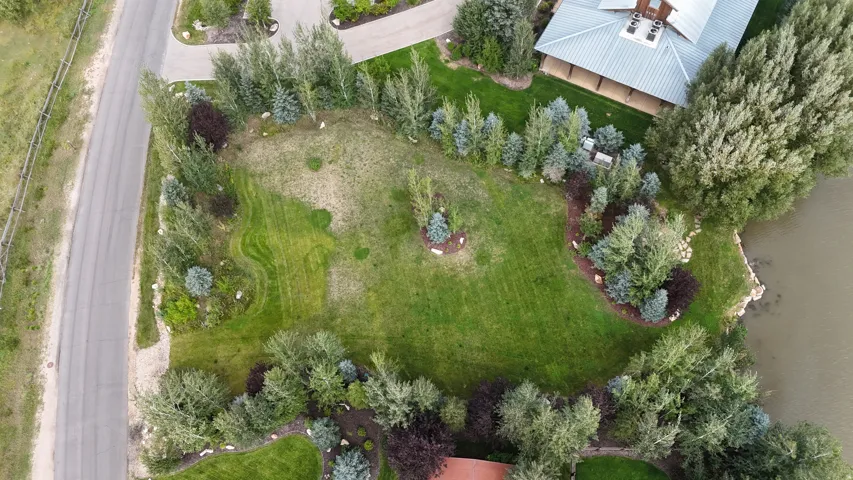 Expansive green space featuring mature trees, landscaped beds, and direct water frontage